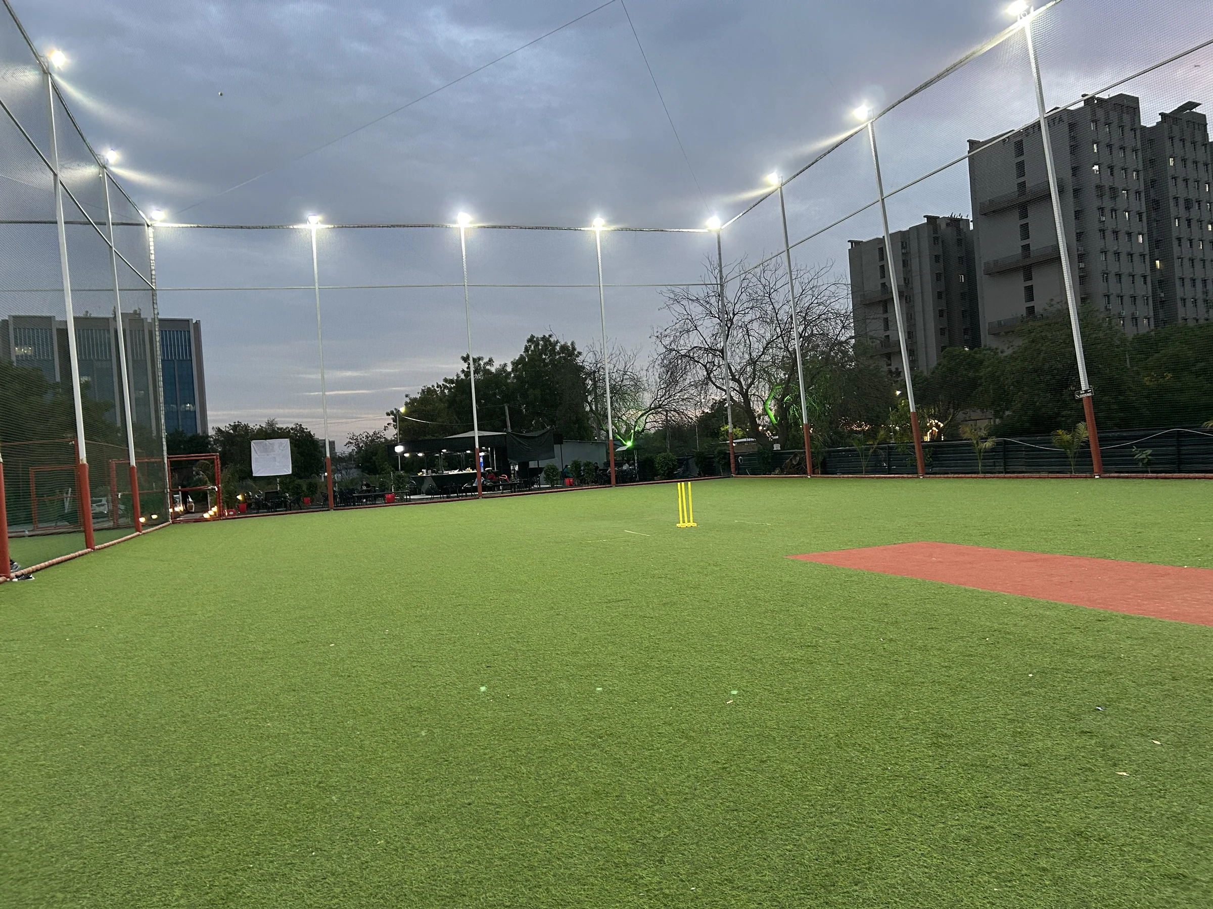 Floodlit outdoor cricket turf surrounded by tall netting