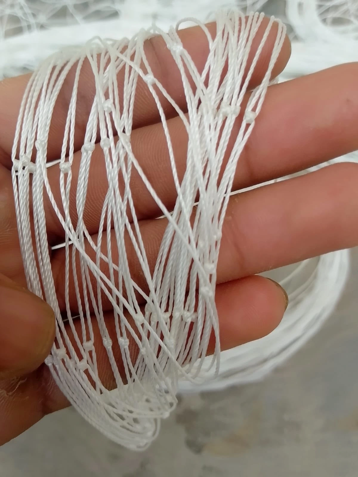 Close-up of white knotted sports net twine held in a hand