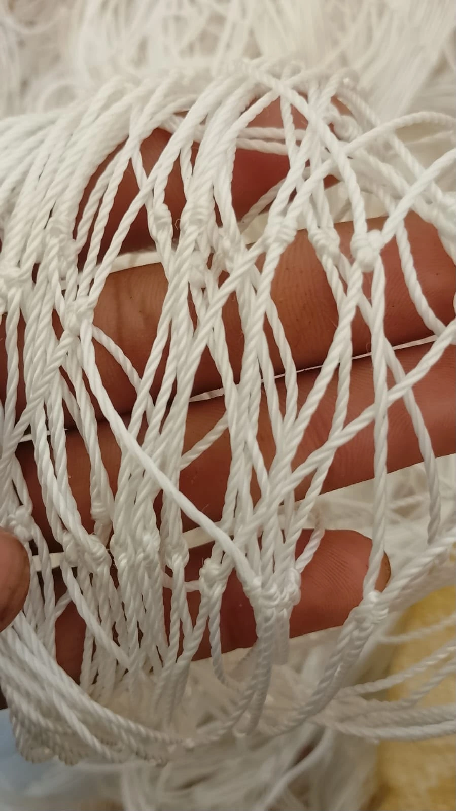 Thick twisted twine of a sports net stretched across fingers
