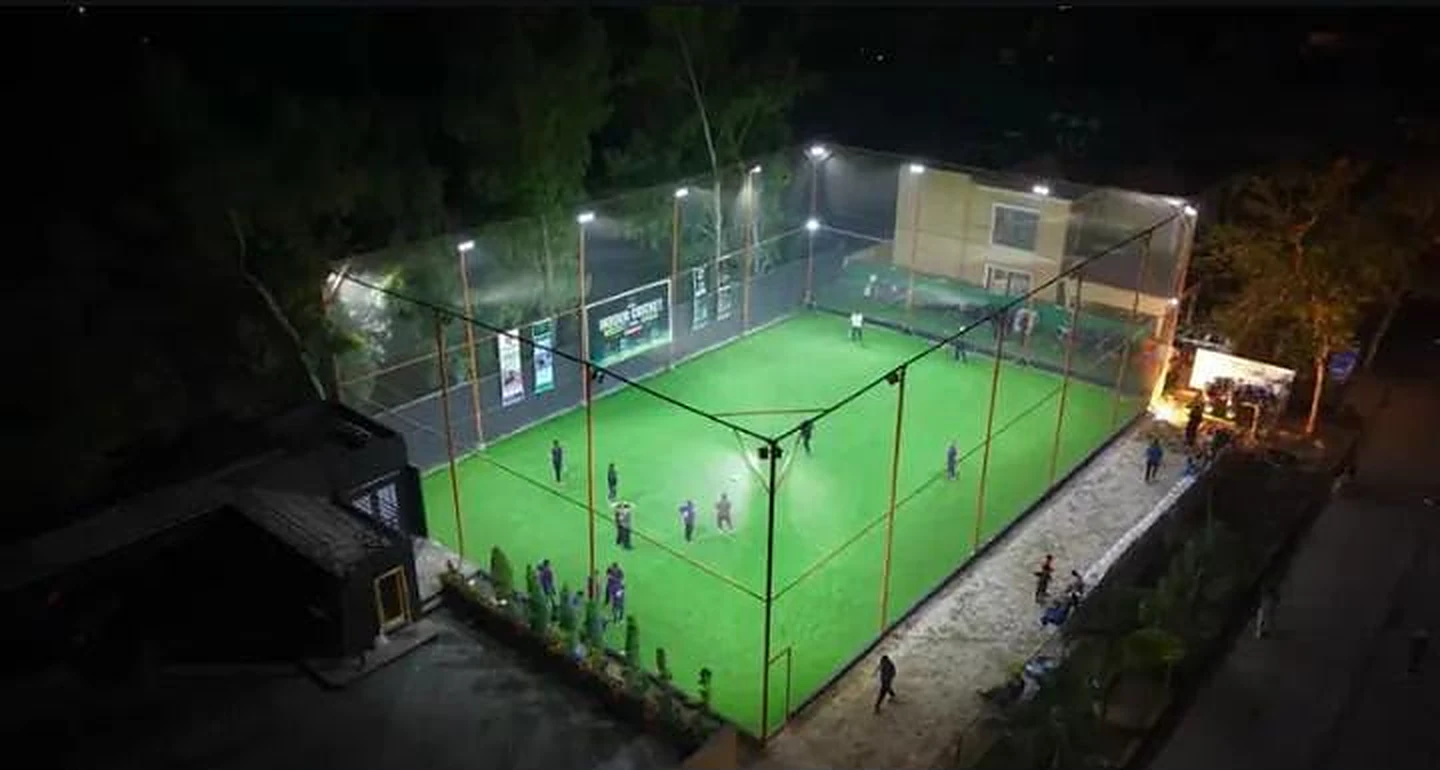 Aerial view of a floodlit football turf ground enclosed by sports netting at night
